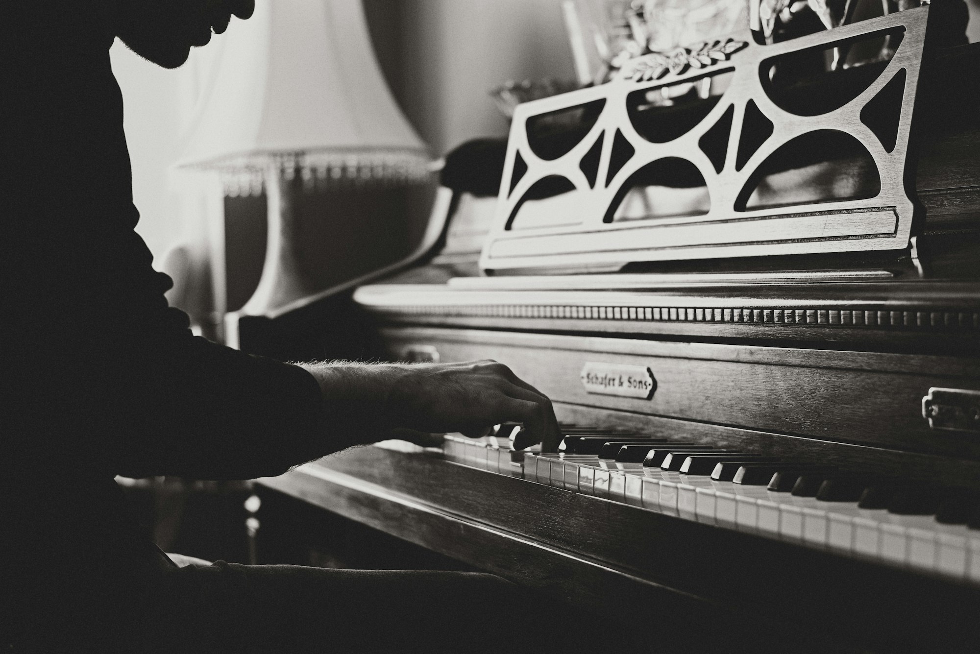 a close-up of hands playing a piano keyboard in black and white